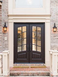 a black double door with two sidelights in front of a brick wall and white pillars