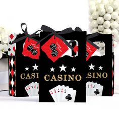 three black casino bags with red and white playing cards on them, sitting next to some candy balls