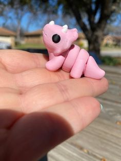 a small pink toy animal sitting on top of someone's hand