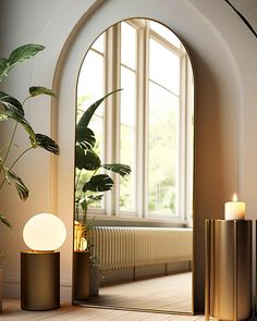 an arch shaped mirror in the middle of a room with two candles and a potted plant next to it