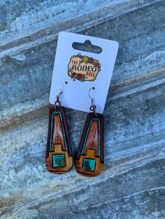 the earrings are made with wood and turquoise glass inlays, on top of a stone surface