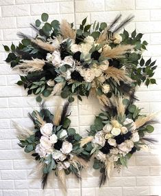 a wreath with flowers and feathers hanging on a brick wall in front of a white brick wall