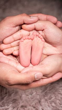 two hands holding a baby's feet in it