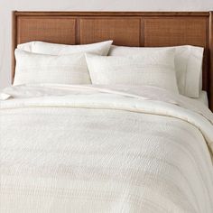 a bed with white linens and pillows on it's headboard in a bedroom