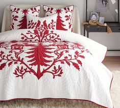 a red and white quilted comforter on a bed in a room with rugs