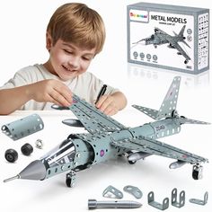 a young boy is playing with a metal model airplane and parts to make it look like he's working on something