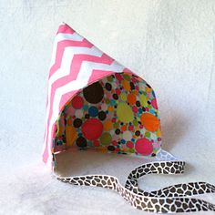 a pink and white chevroned hat with polka dots on the side, next to a leopard print lanyard