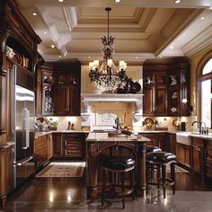 a large kitchen with wooden cabinets and chandelier hanging from the ceiling, along with two bar stools