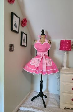 This is such a girly apron that will have you feeling all dressed up while entertaining your guests, creating your favorite culinary delights or just hanging around the house. Full circle skirt, bodice lined with pink gingham fabric, extra-long waist sashes to tie in the front or back, no raw edges. Material: 100% Cotton/ Trim: Poly/Cotton Bias Piping Measurements: Across Bodice: 14 1/2" Neck Ties: 33" Skirt Length: 16" Waist Sashes/Ties: 45" each Top of Bodice to Bottom of Skirt: 29" Fits Sizes S/M/L Best. Can be made in smaller or larger sizes, just contact me Care Instructions: Machine Wah, Cold Water, Delicate Cycle, Line Dry, Iron as Needed Petticoat is used for styling only and not included Girly Apron, Murrells Inlet Sc, Hostess Apron, Murrells Inlet, Sewing Aprons, Full Circle Skirt, Gingham Fabric, Full Circle Skirts, Neck Ties