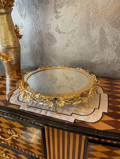 an ornately decorated dresser with a mirror on it's top and a vase in the background