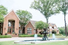 a fountain in front of a large brick house