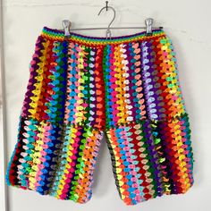 a multicolored knitted shorts hanging on a clothes hanger in front of a white wall