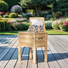 an open wooden box with spoons in it sitting on a wood deck next to flowers