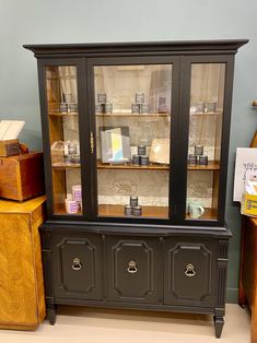 an old china cabinet with glass doors and drawers on the bottom, next to other furniture