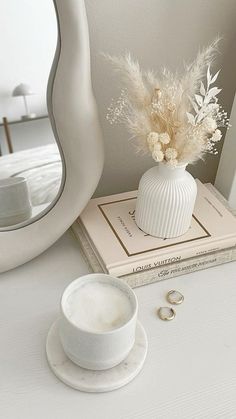 a white vase sitting on top of a table next to a cup and saucer