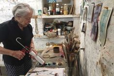 an older woman is painting in her studio