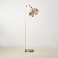 a wooden floor lamp with a metal base and two leaves on the top of it