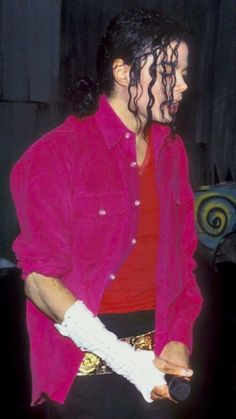 a man with curly hair wearing a red shirt and white gloves