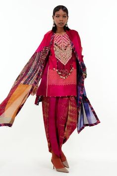 Shocking pink short kurta with all over mixed print, contrast aari, shell, sequin, tassel, mirror and bead embroidered tribal pattern yoke and drop tassel details. Paired with printed pleated cowl draped trouser and beaded bordered dupatta.
Components: 3
Pattern: Printed and Embroidered
Type Of Work: Mixed Print, Aari, Shell, Sequin, Tassel, Mirror and Bead Work
Neckline: Round Neck
Sleeve Type: Full Sleeves
Fabric: Mushroom Twill, Cotton Silk, Sheer Silk
Color: Pink
Other Details: 
Beaded kurta Bohemian Pink Salwar Kameez With Mirror Work, Pink Bohemian Traditional Wear With Printed Motifs, Bohemian Pink Traditional Wear With Printed Motifs, Bohemian Embroidered Pink Salwar Kameez, Bohemian Pink Embroidered Salwar Kameez, Bohemian Pink Salwar Kameez With Zari Work, Bohemian Pink Salwar Kameez With Resham Embroidery, Bohemian Silk Salwar Kameez With Mirror Work, Bohemian Pink Salwar Kameez With Dupatta