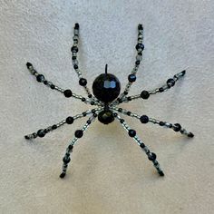 a black spider made out of beads on a white surface