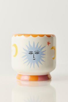 a ceramic cup with an image of a face on the side and stars in the middle