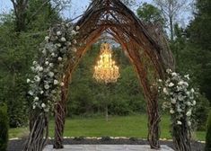 an outdoor wedding arch with flowers and chandelier