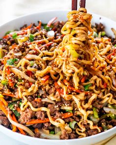 a bowl filled with noodles, meat and veggies on top of a table