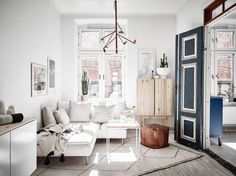 a living room filled with white furniture and lots of window panes on the wall