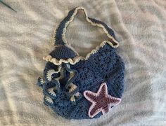 a crocheted bag with a starfish on it laying on top of a bed