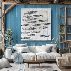 a living room with blue walls and white furniture in the center, along with fish paintings on the wall