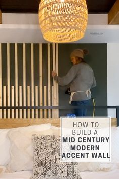 a woman standing in front of a bed with pillows on it and the words how to build a mid century modern accent wall