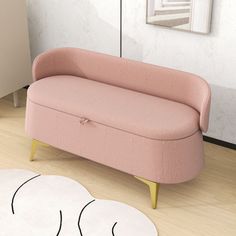 a pink couch sitting on top of a hard wood floor next to a white rug