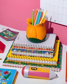 there are many school supplies on the desk and one has a pencil holder in it