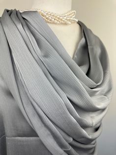 a gray dress with a pearl necklace on it's neck and white pearls hanging from the back