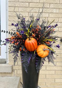 a black vase filled with lots of flowers and pumpkins on top of a table