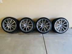 four rims and tires are lined up against the wall