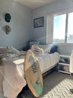 a bedroom with a surfboard on the bed and other items in the room around it