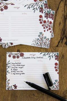 two notepads sitting on top of a wooden table next to a pen