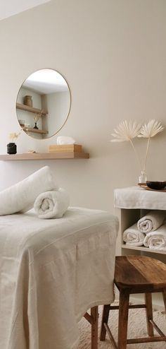 a bedroom with white linens on the bed and wooden stool in front of it