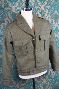 ABOUT THIS STYLE: Cut from English woven wool melton in a gorgeous melange of colors with solid brushed brass buttons. This military style blouson is just about the most comfortable style of outerwear possible. It is boxy in the chest and shoulder and fitted at the waistband. Perfect for just about any winter activity. This is a completely customized version of the jacket that Dwight Eisenhower had made for himself to wear during WWII that we made for one of our clients. We can make this in any Wool Collared Blazer With Buttons, Khaki Wool Pea Coat With Pockets, Tweed Outerwear With Lapel Collar And Buttons, Wool Tweed Jacket With Welt Pockets, Wool Tweed Jacket With Pockets, Winter Wool Tweed Jacket With Button Cuffs, Khaki Wool Outerwear With Buttons, Military Style Outerwear With Welt Pockets For Winter, Wool Tweed Jacket With Lapel Collar And Flap Pockets