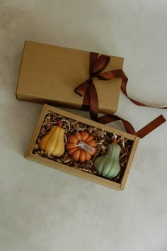 two small pumpkins in a box with a brown ribbon