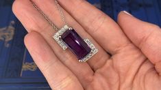 This stunning 14K white gold pendant is centered with one (1) cut-cornered rectangular step cut natural amethyst set into a four-prong setting. The amethyst is bordered with eighteen (18), bead set, round brilliant cut diamonds. The pendant measures 27.0mm X 16.9mm X 13.3mm and is suspended from a 14K white gold cable link style neck chain measuring 18 inches in length. Formal Rectangular Fine Jewelry Gemstones, Luxury Purple Diamond-cut Jewelry, Elegant Rectangular Gemstones For Formal Occasions, Elegant Rectangular Gemstones For Formal Events, Formal Amethyst Jewelry With Polished Finish, Elegant Purple Jewelry With Polished Finish, Luxury Rectangular Amethyst Jewelry, Formal Purple Jewelry With Polished Finish, Luxury Purple Rectangular Jewelry