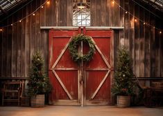 an old barn with christmas wreaths and lights on the doors is decorated for holiday