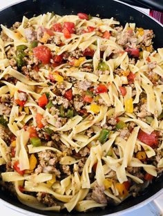 a skillet filled with pasta, meat and vegetables