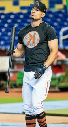 a man holding a baseball bat on top of a field in front of an empty bleachers