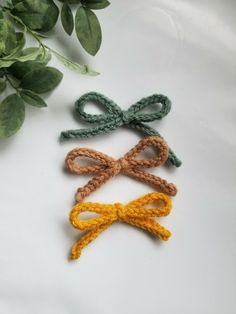 three crocheted bows tied to each other on a table next to some leaves