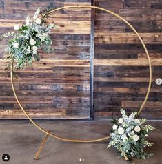 two white flowers are placed in the middle of a circular stand with wooden planks