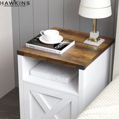 a table with a book, cup and saucer on it next to a lamp