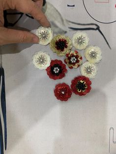 the person is making crochet flowers out of yarn and plastic beads with scissors