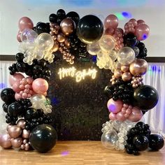 an arch made out of balloons with the word happy written on it in gold and black